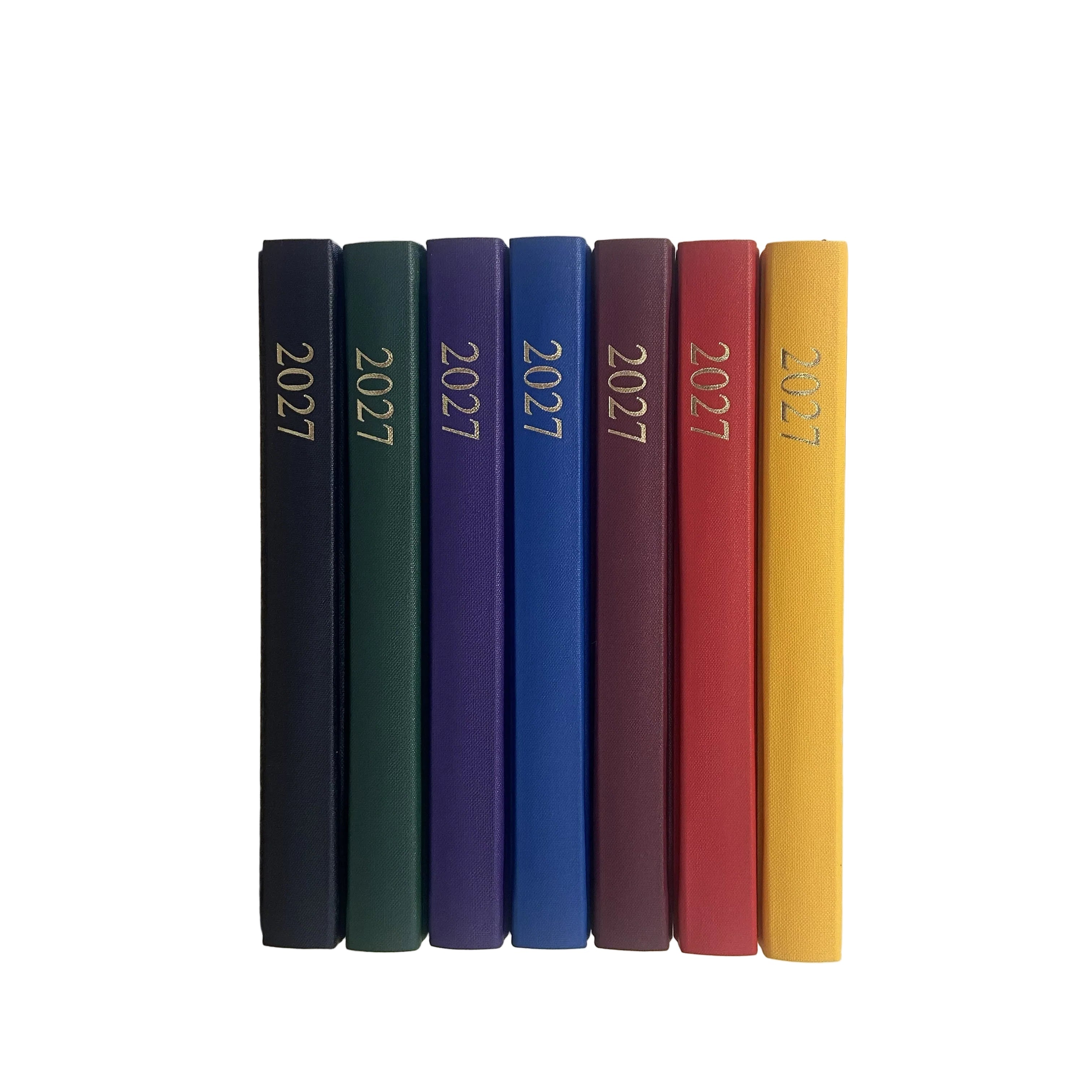 A stack of seven hardcover planners or books with the year '2027' embossed on the spines, shown in yellow, red, burgundy, blue, purple, green, and black, arranged vertically on a white background.