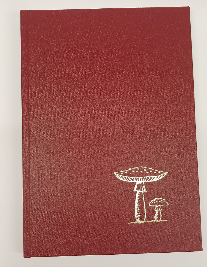 Red notebook with gold mushroom illustration on a white background