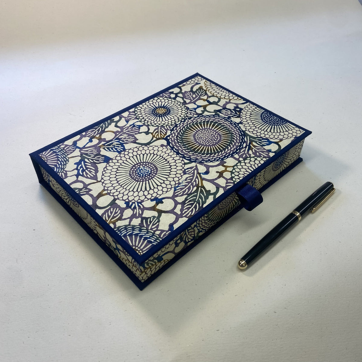 Luxury Writing Box with an intricate navy blue and cream floral mandala pattern, shown next to a black pen