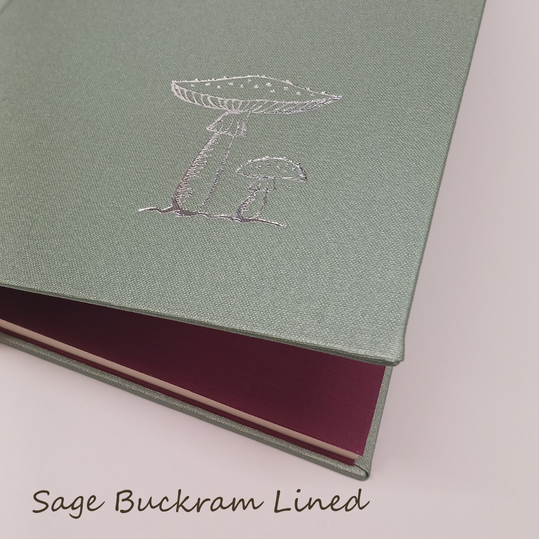 Green notebook with mushroom design and maroon interior on a light pink background